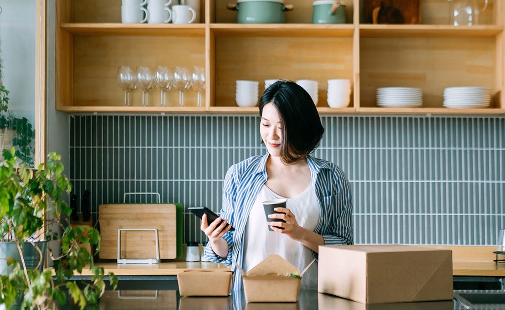 woman using phone and holding cup