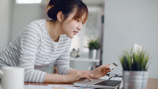 woman looking at laptop holding credit card
