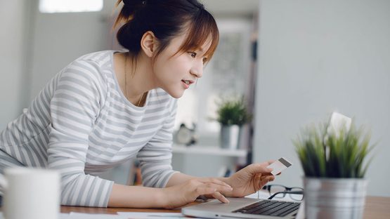 woman looking at laptop holding credit card