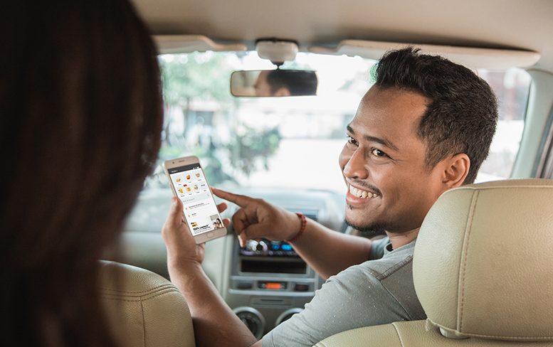 Asian driver looking back at passenger to chat