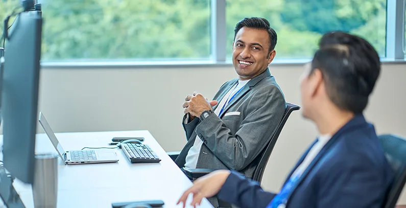 A man smiling at a colleague in office