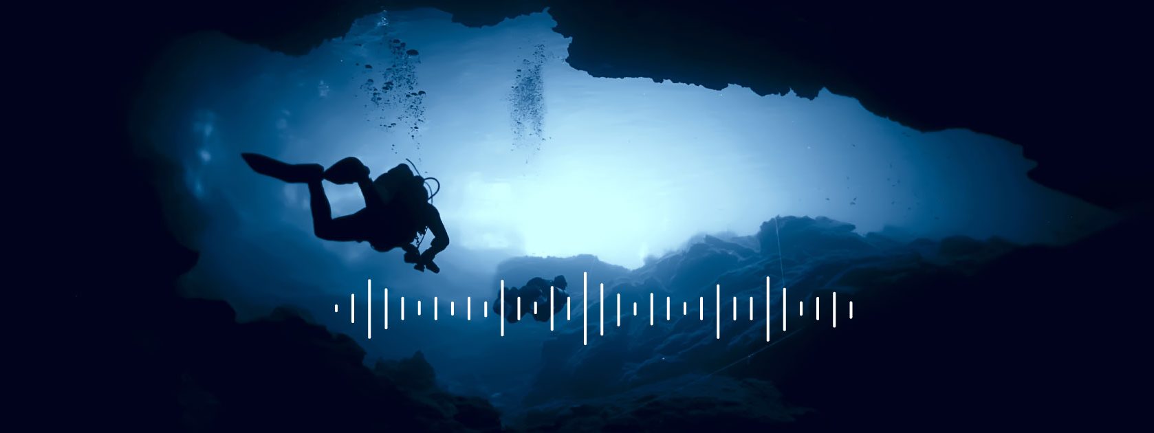 divers swimming in an underwater cave