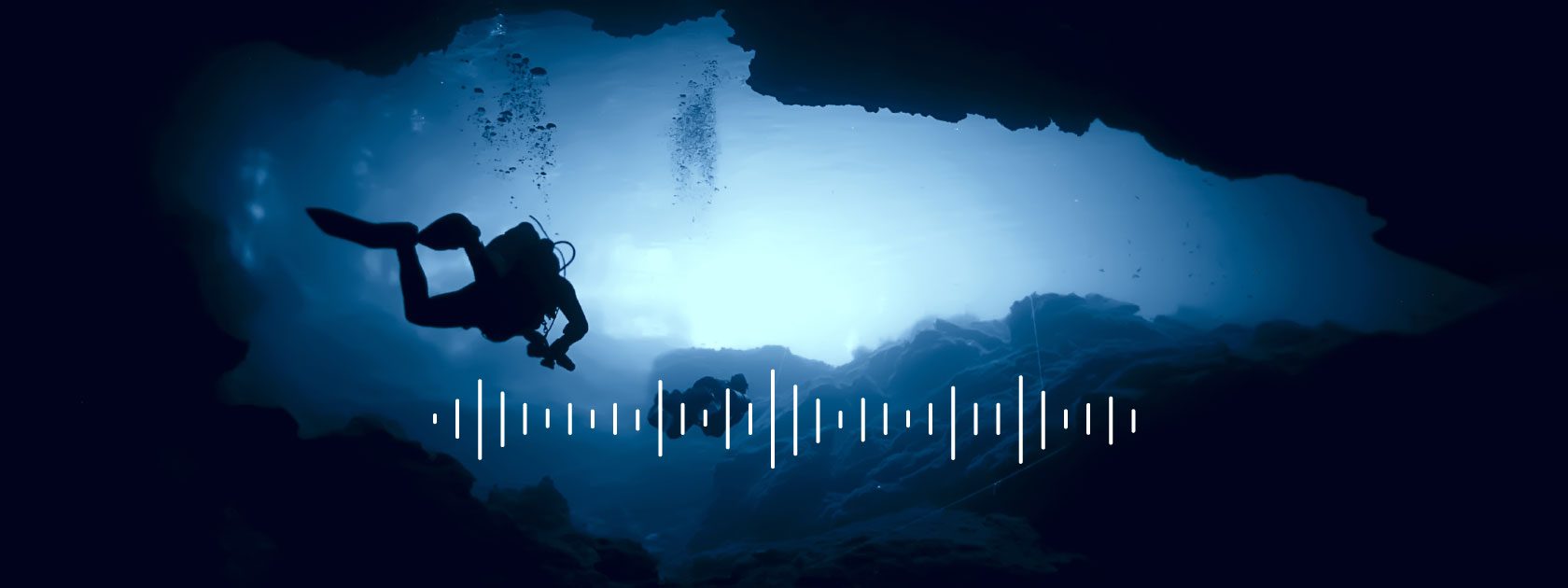 divers swimming in an underwater cave