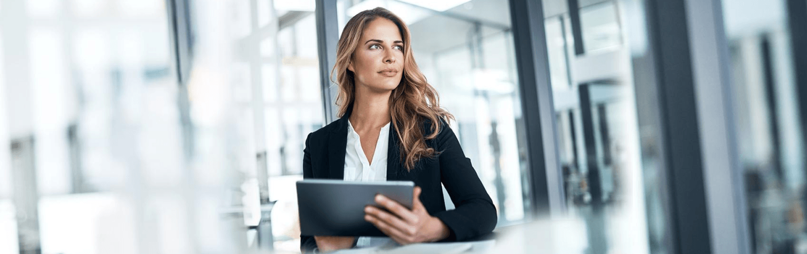 A woman in a black blazer and white shirt, holding an ipad masthead