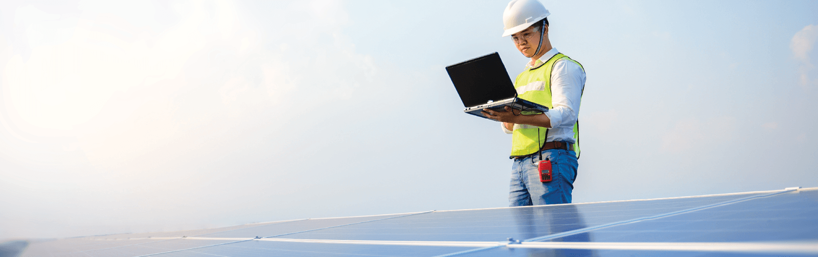 A man holding a laptop with solar panels in front 