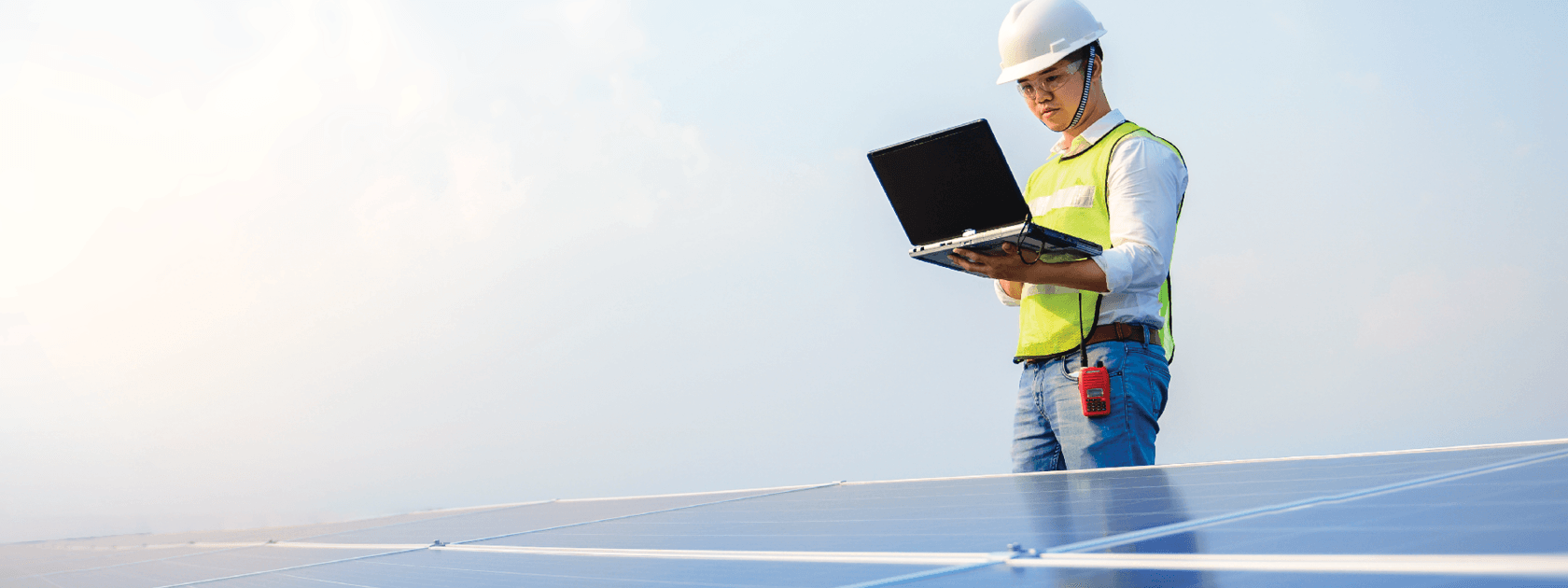 A man holding a laptop with solar panels in front