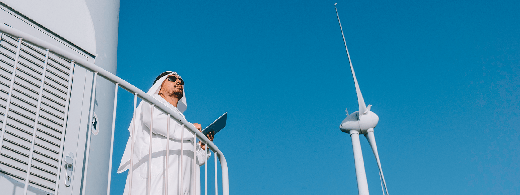 An Arab man with an ipad and a windmill in the background