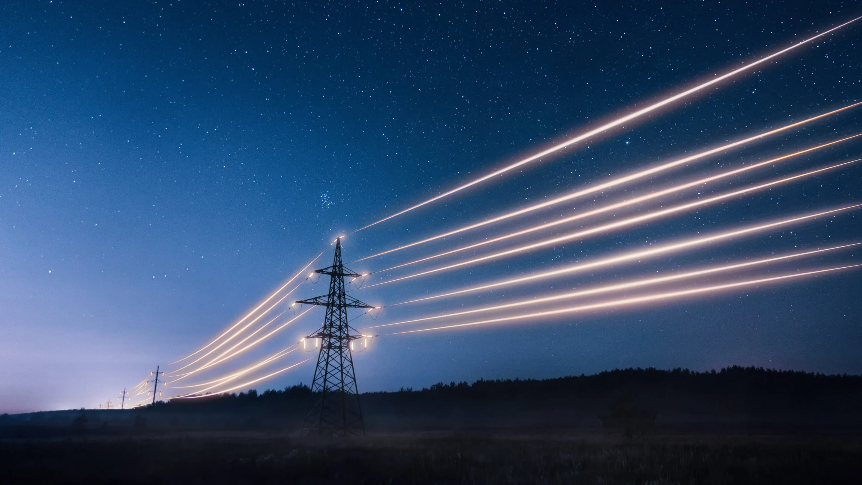 Power transmission lines illuminated against a starry night sky.