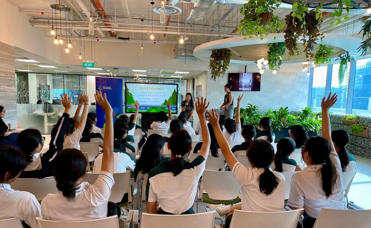 A group of woman raise their hands in a session to ask questions to the speaker