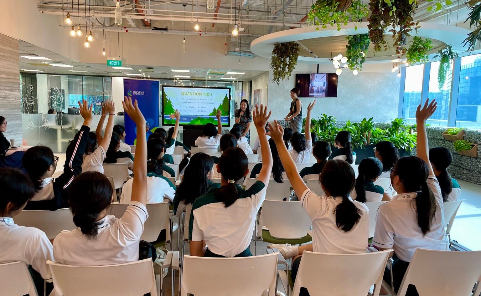 A group of woman raise their hands in a session to ask questions to the speaker