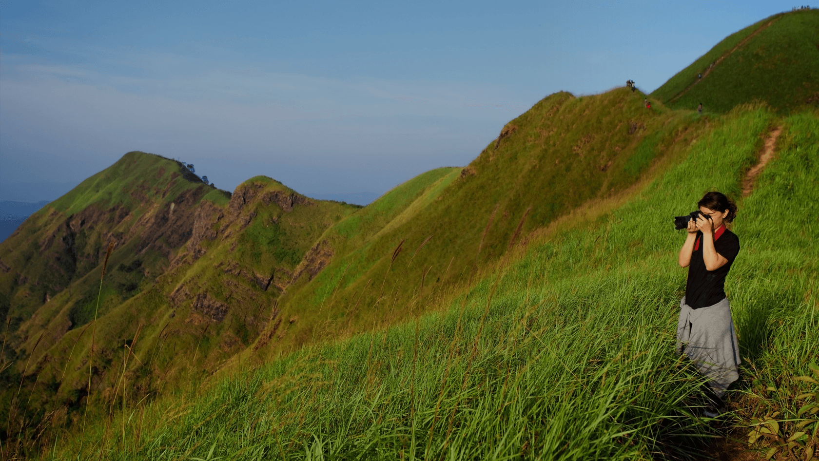 A girl taking photos on the green mountains