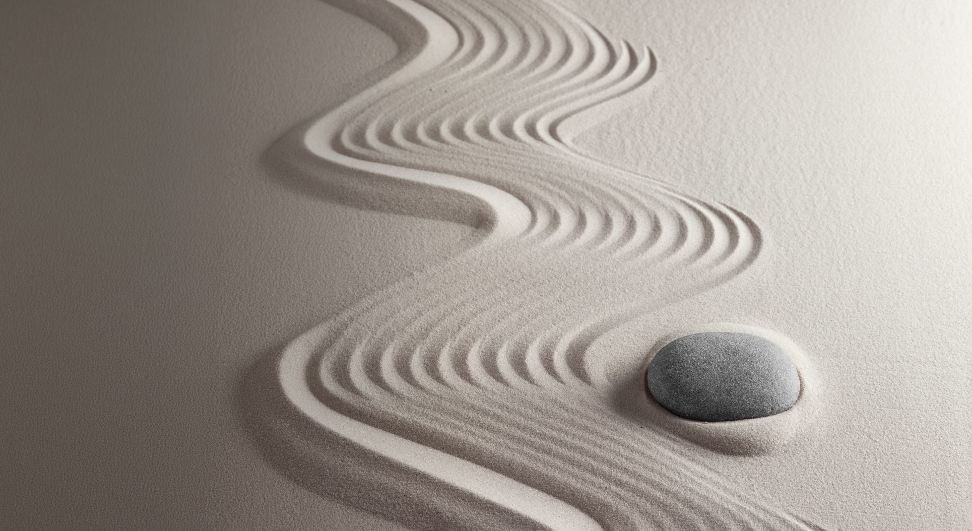 Abstract curved lines creating a wave-like pattern and a pebble in textured sand.