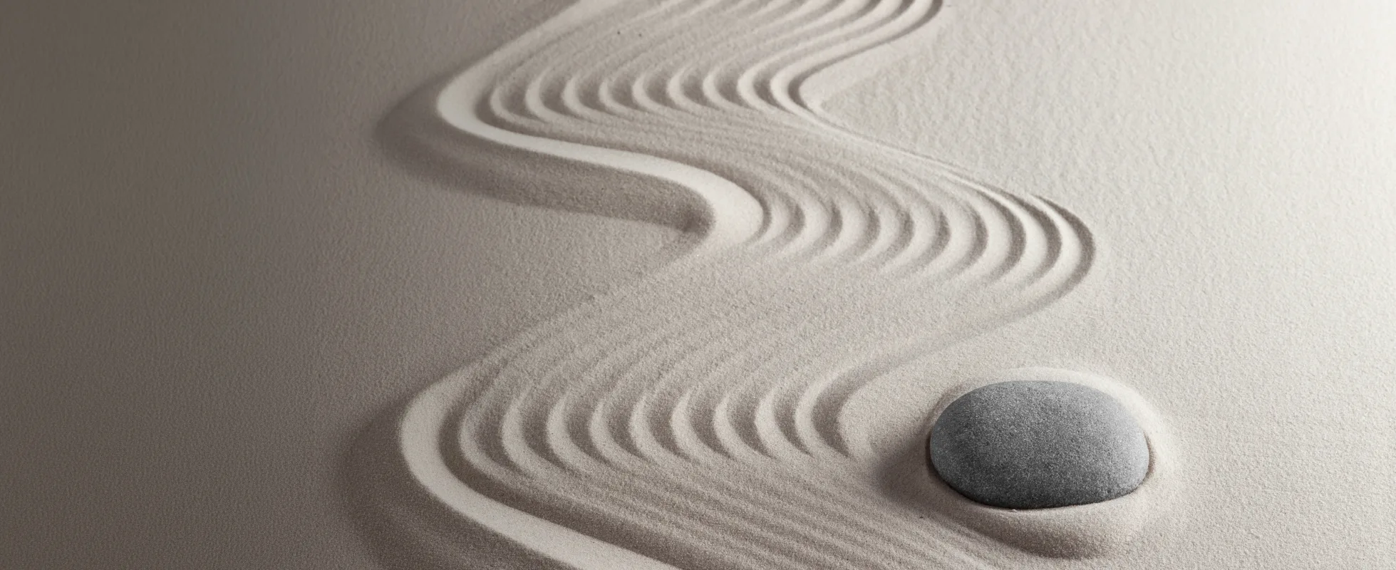 Abstract curved lines creating a wave-like pattern and a pebble in textured sand.