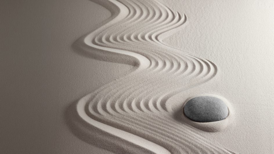 Abstract curved lines creating a wave-like pattern and a pebble in textured sand.
