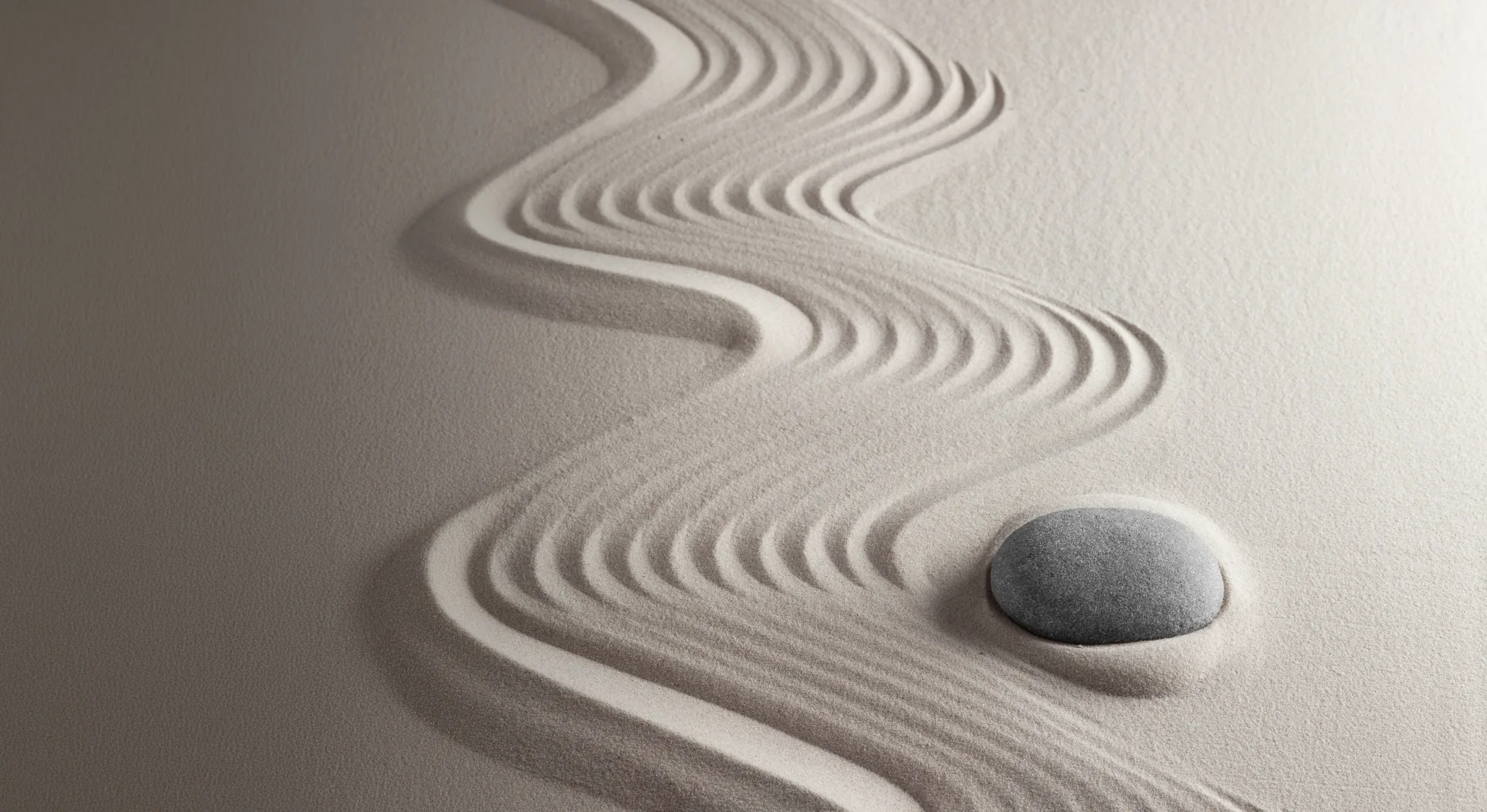 Abstract curved lines creating a wave-like pattern and a pebble in textured sand.