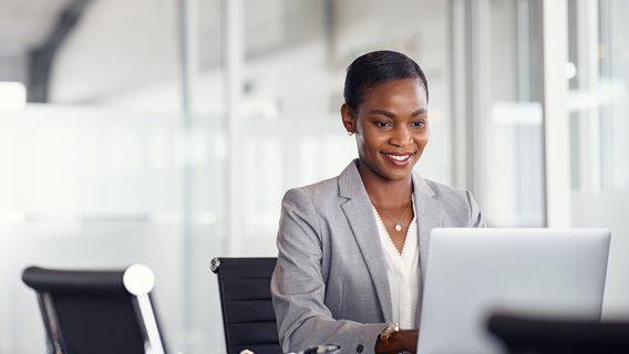 A smiley middle aged corporate girl looking at her laptop