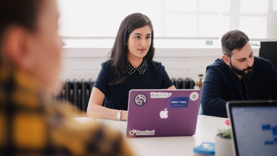 Young woman sat as a table with a laptop amongst others
