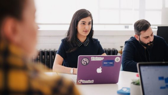Young woman sat as a table with a laptop amongst others
