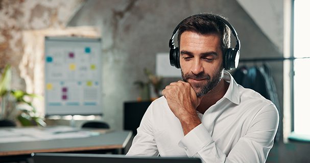 A man in office with headphones listening to music or podcast