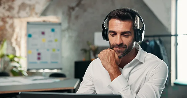A man in office with headphones listening to music or podcast