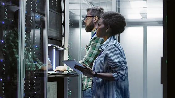 Two colleagues look at cybersecurity in a data room.