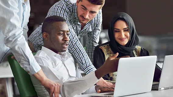 Colleagues review insights together around a laptop.