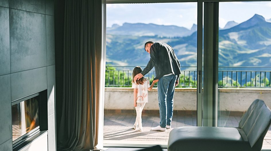 A man and a child speaking and overlooking a landscape view of mountains