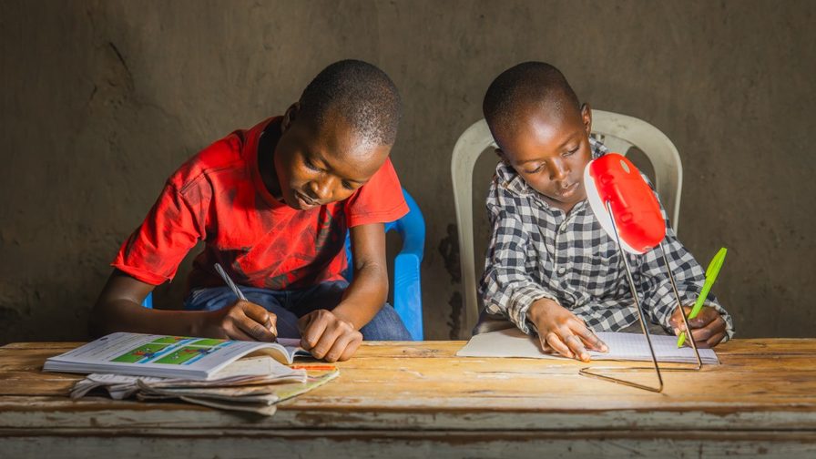 2 african children sitting by a lamp and drawing