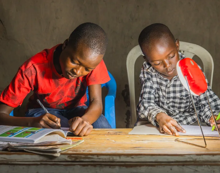 2 african children sitting by a lamp and drawing