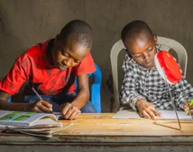 2 african children sitting by a lamp and drawing