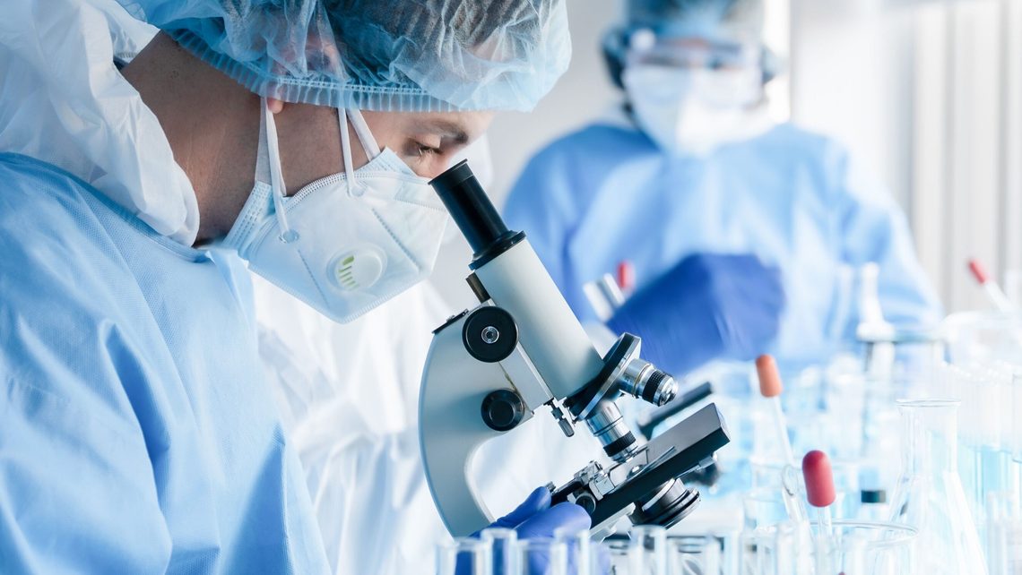 image of scientist looking through a microscope in a laboratory