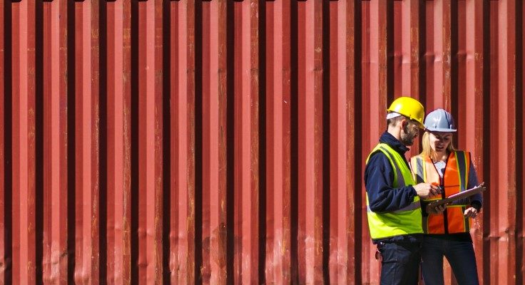 2 people in hardhats standing in front of a container