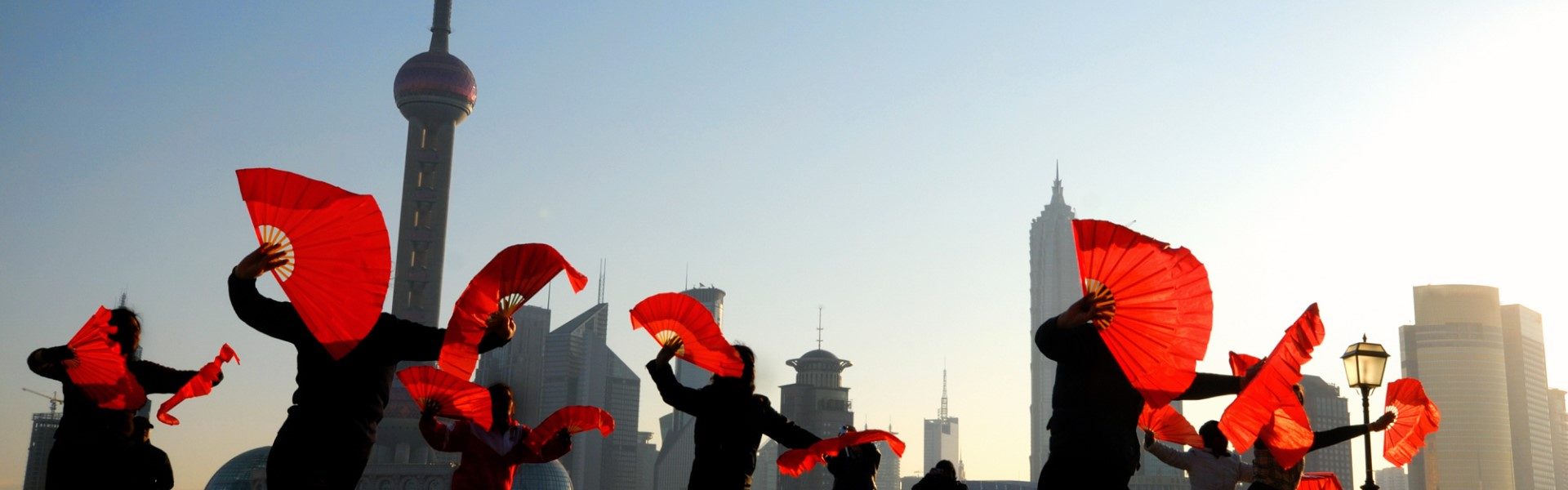 group of dancers holding red fans along Shanghai Bund