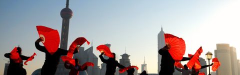 group of dancers holding red fans along Shanghai Bund