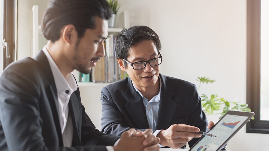 Two colleagues interacting over data displayed in a tab