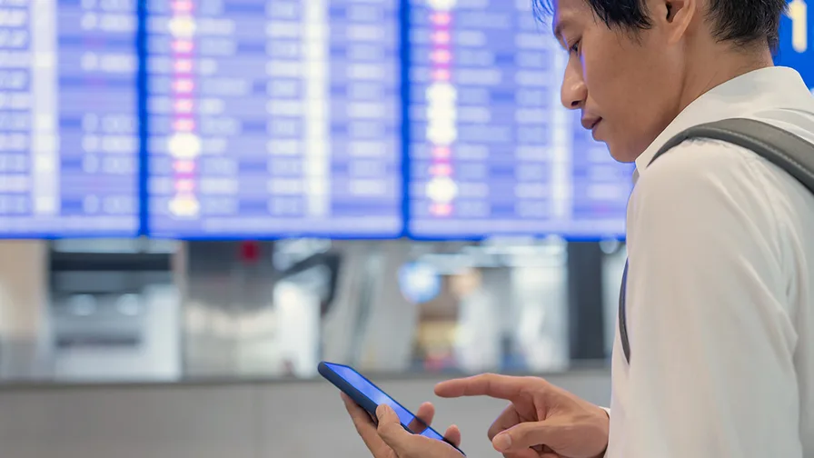Man at airport looking at  phone