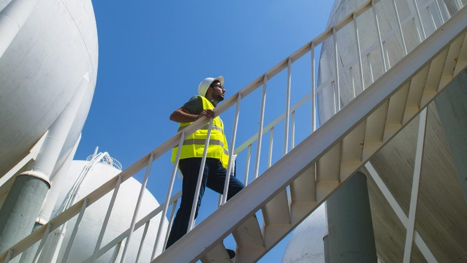 close of industrial tanks with man climbing up ladder