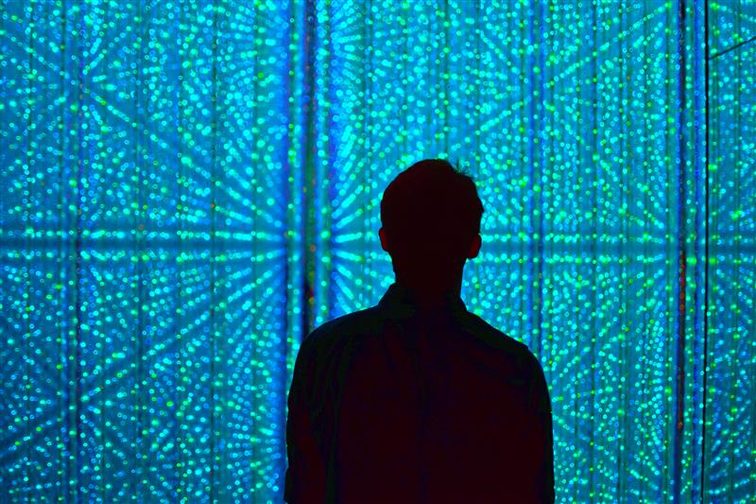 silhouette of man standing in front of a wall of lights