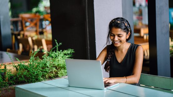 Young lady sat smiling at her laptop