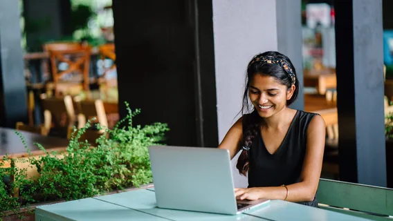 Young lady sat smiling at her laptop