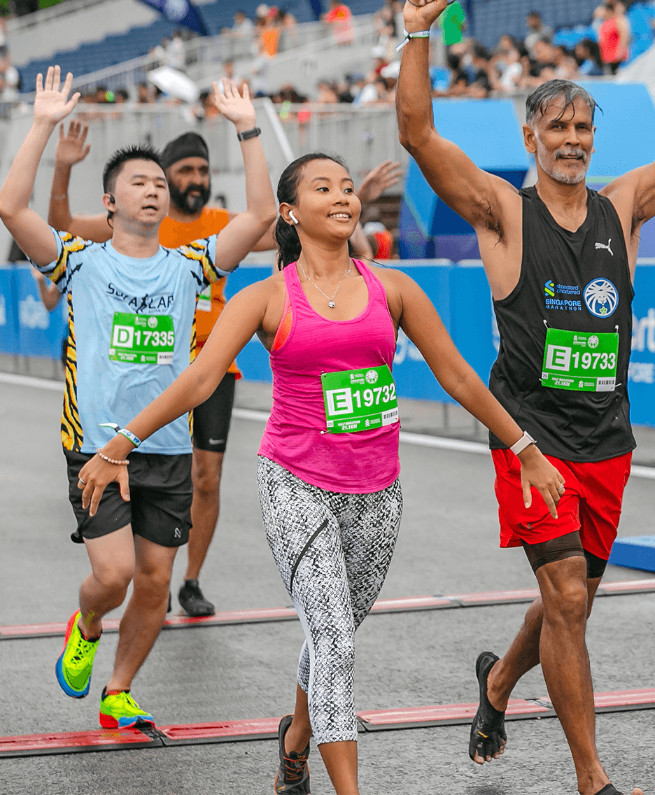 A woman in a pink top crosses the finish line of the Standard Chartered Singapore marathon.