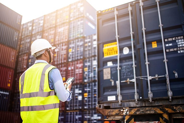 Worker wearing high visibility vest in front of containers