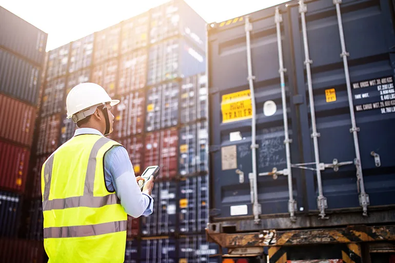 Worker wearing high visibility vest in front of containers