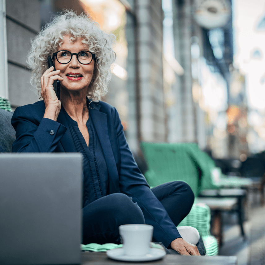 A financier takes a phone call in front of her laptop at a cafe.