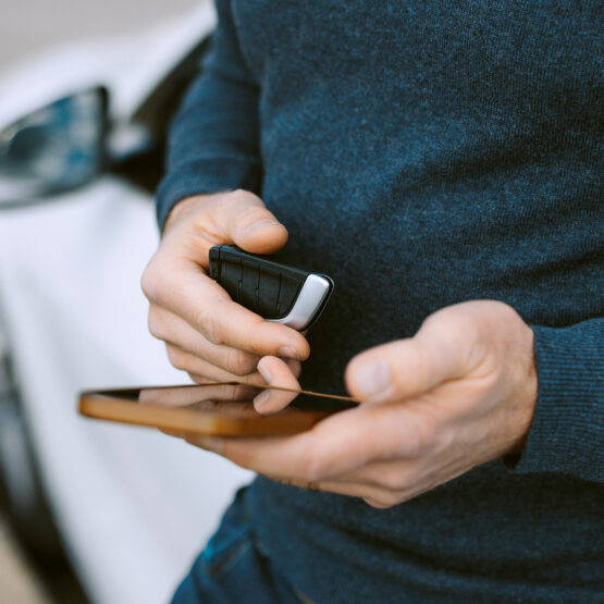 Man with car key using mobile phone