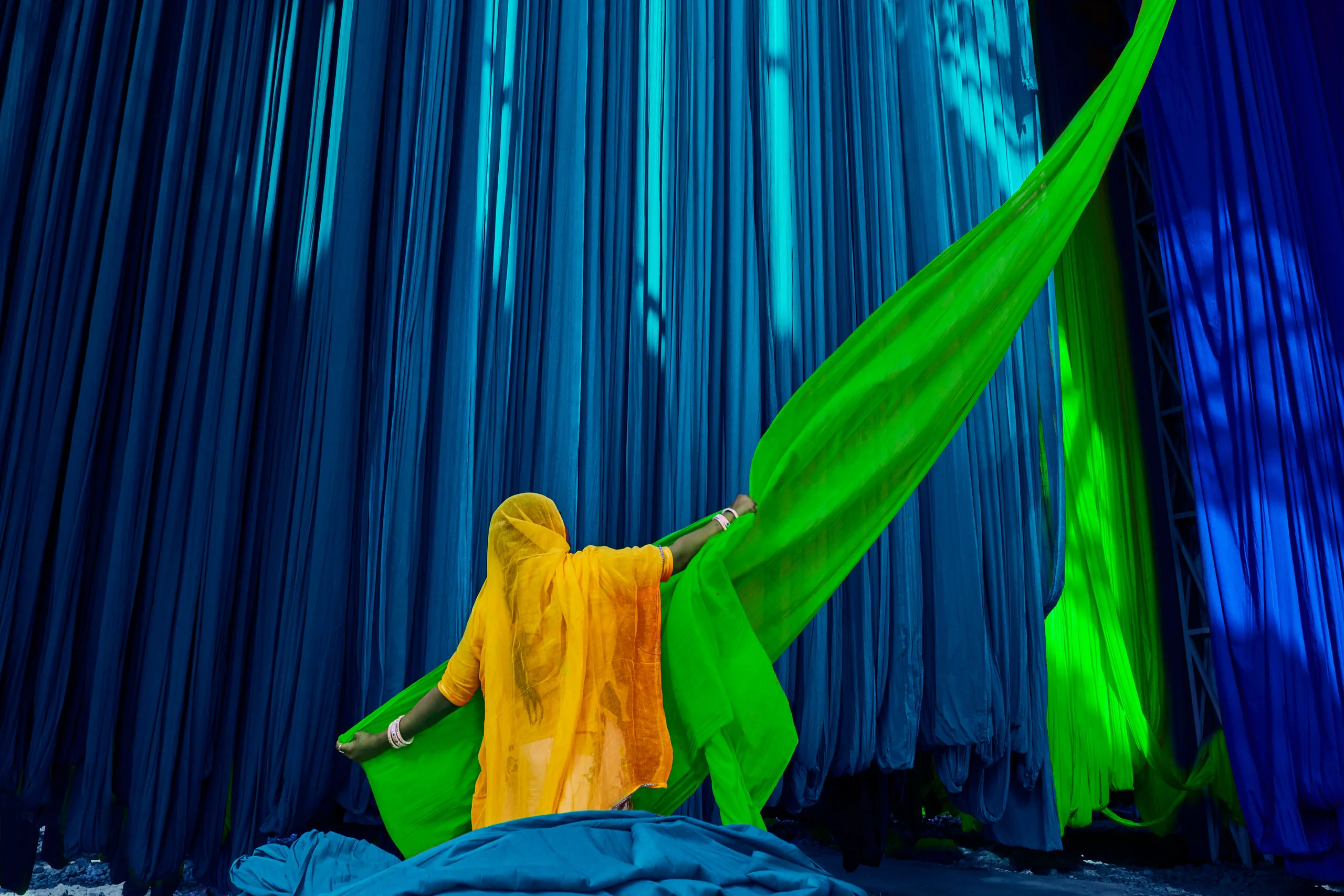 image of Indian lady pulling at a ream of fabric